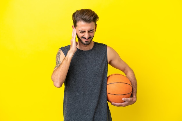 Красивый молодой баскетболист, изолированный на желтом фоне, расстроен и закрывает уши