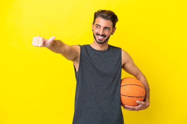 Handsome young basketball player man isolated on yellow background giving a thumbs up gesture