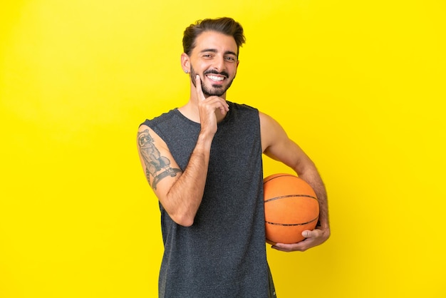Красивый молодой баскетболист, изолированный на желтом фоне, думает об идее, глядя вверх