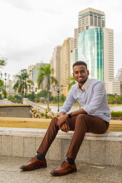 Handsome young black businessman at park outdoors during summer