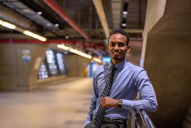 Handsome young black businessman wearing shirt and tie in station platform horizontal shot