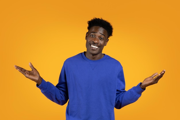 Handsome young black man spread hands sideways yellow background