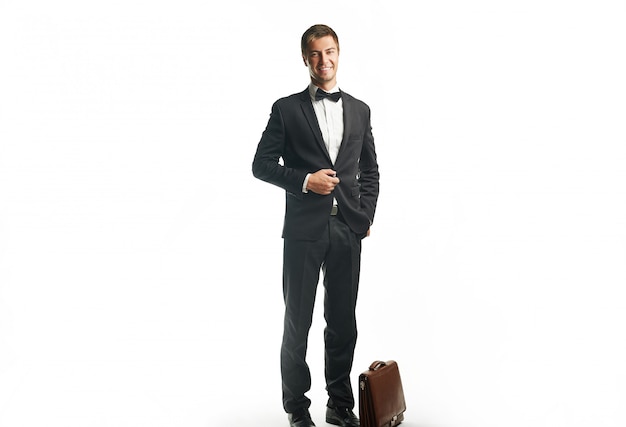 Handsome young business man in black suit holding a suitcase