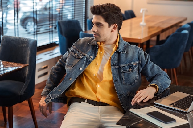 handsome young business man sitting in cafe indoors using laptop computer.