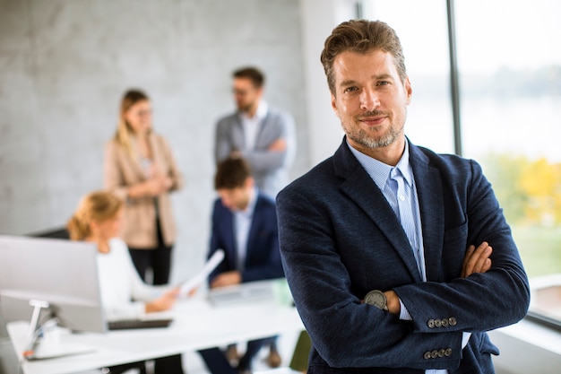 Photo handsome young business man standing confident in the office in front of his team