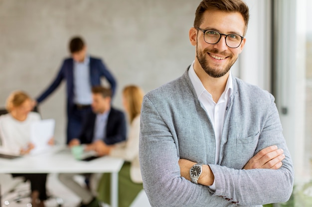 Handsome young business man standing confident in the office in front of his team