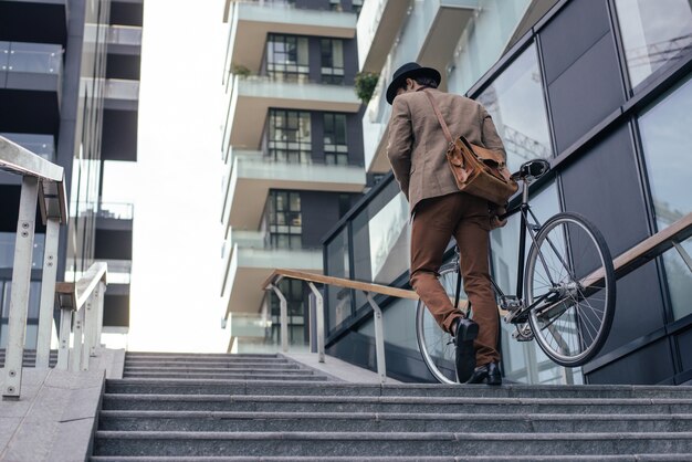 彼の現代の自転車でハンサムな若いビジネスマン。