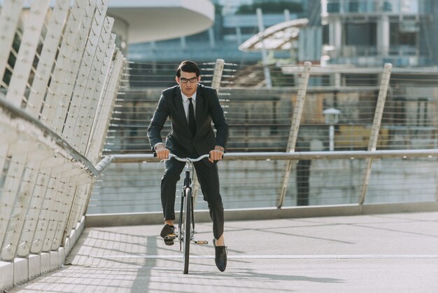 Красивый молодой бизнесмен с его современным велосипедом.