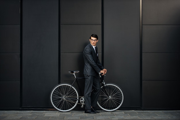 Handsome young business man with his modern bicycle.