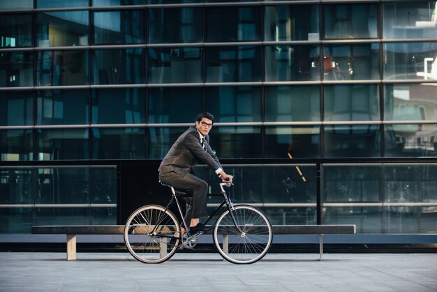 彼の現代の自転車を持つハンサムな若いビジネスマン。