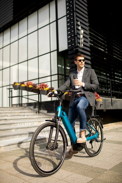 테이크 아웃 커피 컵 ebike에 잘 생긴 젊은 사업가