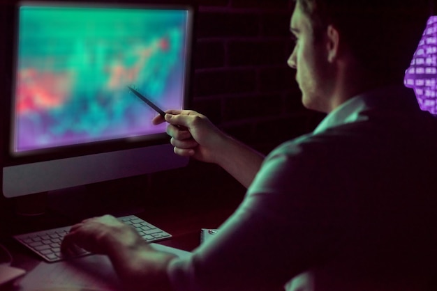 Handsome young businessman is working with computer in office at night