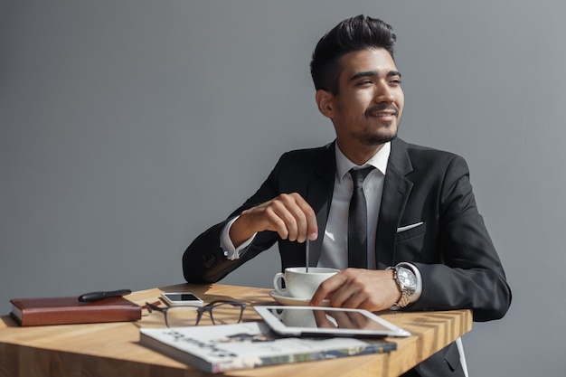 Handsome young businessman sitting in cafe and drinking coffee