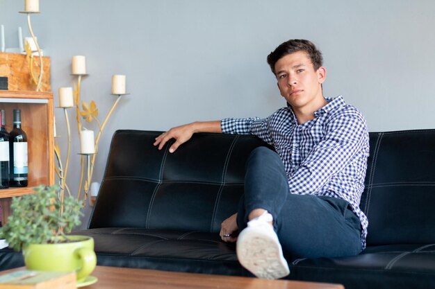 Handsome young businessman sitting on elegant sofa next to elegant table with wine