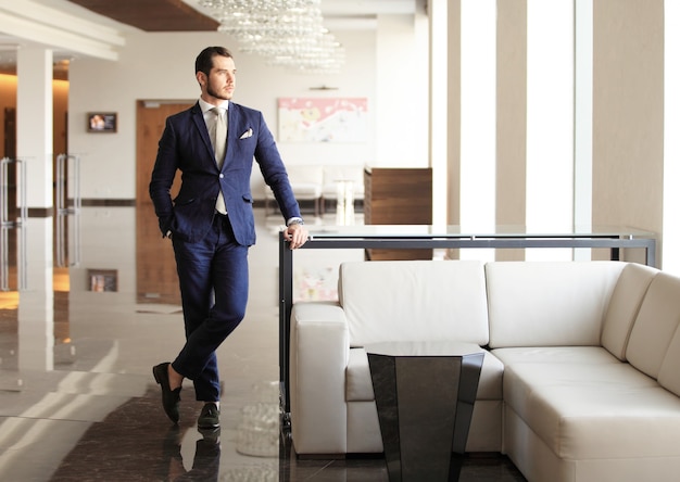 Handsome young businessman in a stylish modern office space with large windows