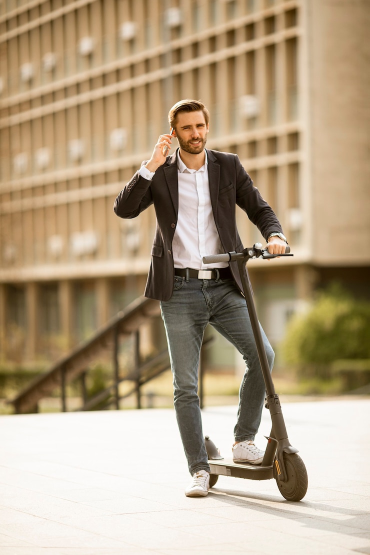 Photo handsome young businessman using mobile phone  on electric scooter