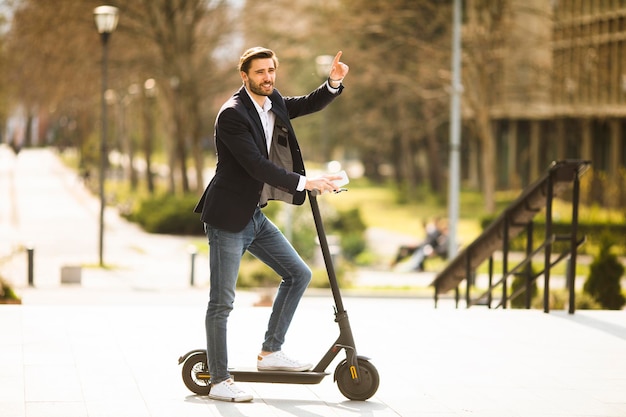 Handsome young businessman using mobile phone  on electric scooter