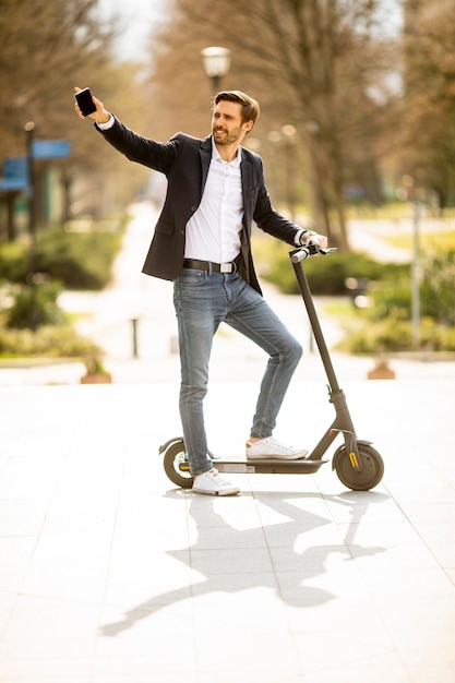 Handsome young businessman using mobile phone  on electric scooter