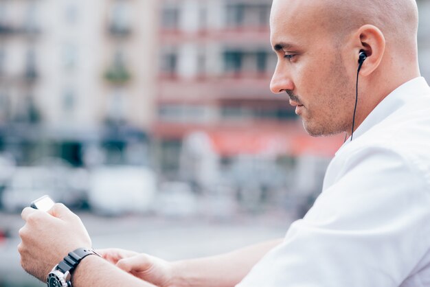 Photo handsome young businessman in a white shirt leaned on handrail and listening to music