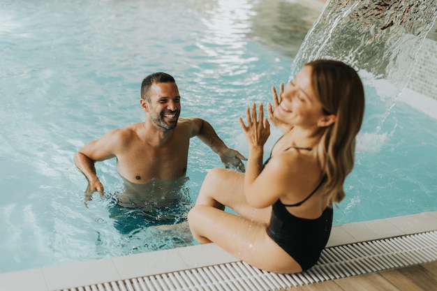 Handsome young couple having fun in the indoor swimming pool