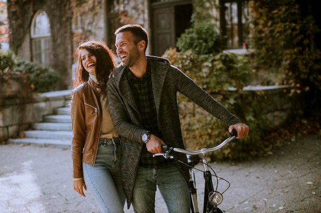 Handsome young couple walking with bicycle in autumn park