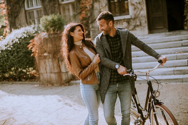 Handsome young couple walking with bicycle in autumn park