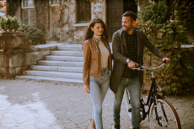 Handsome young couple walking with bicycle in autumn park