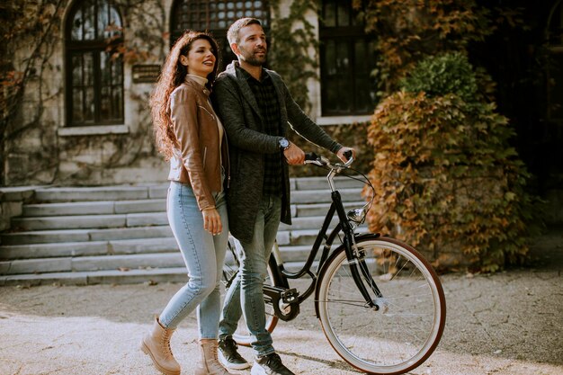 Handsome young couple walking with bicycle in autumn park