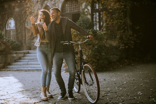 Handsome young couple walking with bicycle in autumn park