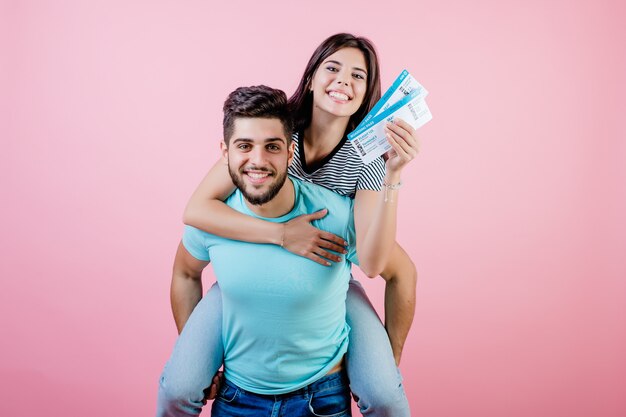 Handsome young couple with plane tickets, boyfriend holding\
girlfriend imitating airplane