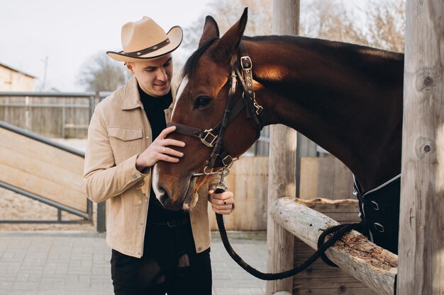 Handsome young cowboy on a ranch with a horse