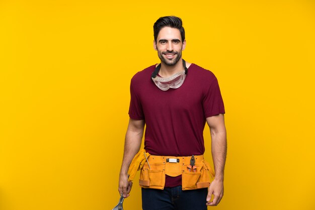 Handsome young craftsman over isolated yellow 