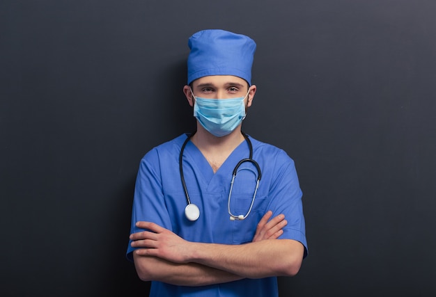 Handsome young doctor in blue medical uniform and mask.