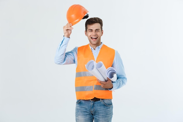 Handsome young engineer man over grey wearing safety helmet with shocked surprise face