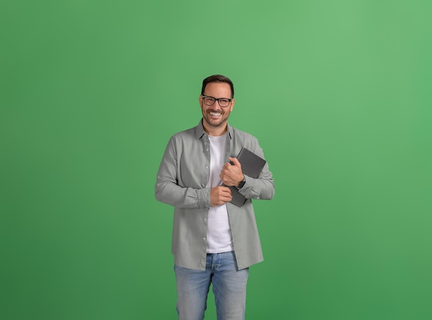 Handsome young entrepreneur with digital tablet posing confidently over isolated green background