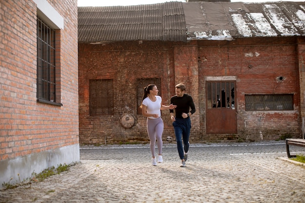 Handsome young fitness couple running in urban area