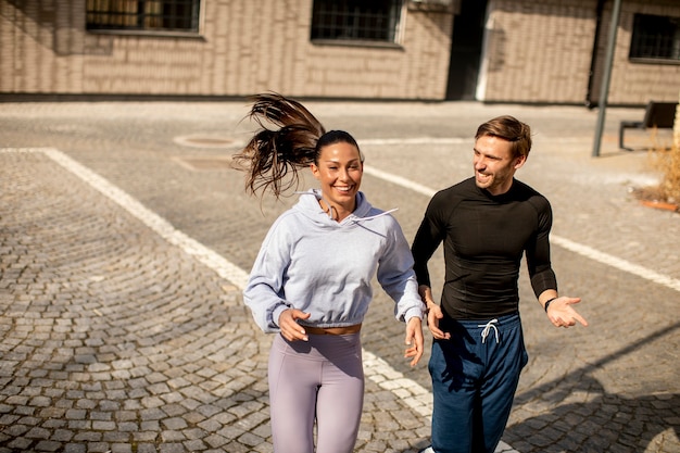 Photo handsome young fitness couple running in urban area