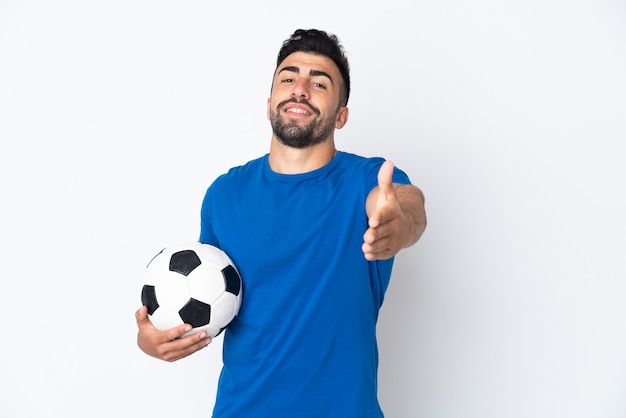 Handsome young football player man over isolated wall shaking hands for closing a good deal