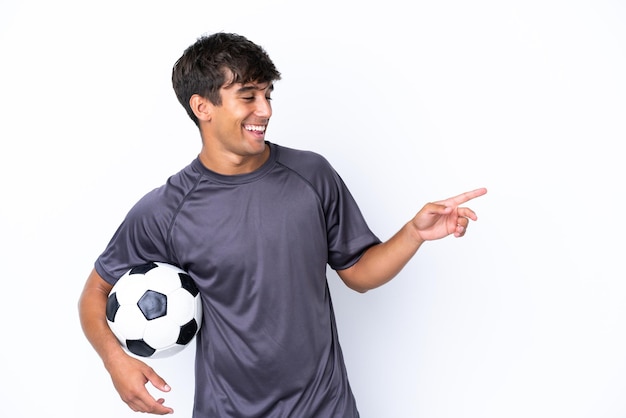 横に指を指し、製品を提示する白い背景で隔離のハンサムな若いサッカー選手の男