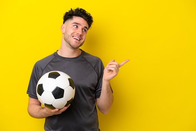 Handsome young football player man isolated on yellow background intending to realizes the solution while lifting a finger up