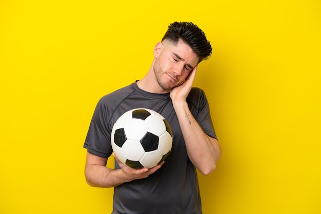 Handsome young football player man isolated on yellow\
background with headache