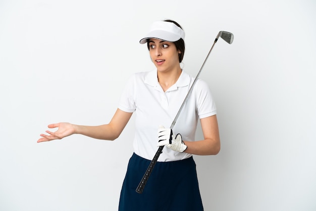 Красивая молодая женщина-игрок в гольф изолирована на белом фоне с удивленным выражением лица, глядя в сторону