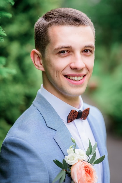 Handsome young groom in grey suit with orange boutonniere