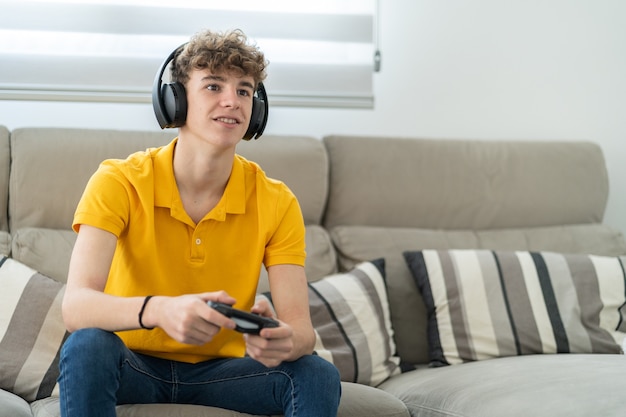 Handsome young guy playing a game console with headphone and\
controller in his living room