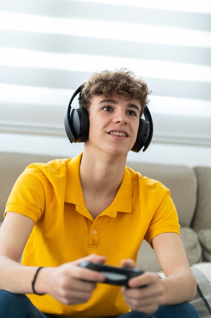 Photo handsome young guy playing a game console with headphones and controller in his living room