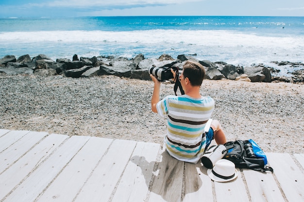 写真 ハンサムな若い男ビーチでラップトップを使っている写真家