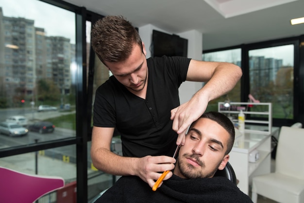 Handsome Young Hairdresser Giving A New Haircut To Male Customer At Parlor