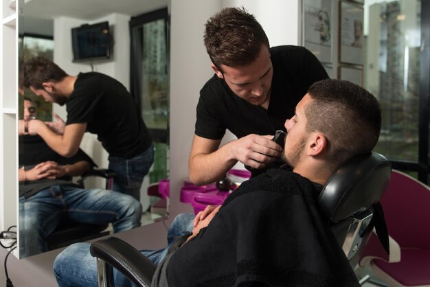 Handsome Young Hairdresser Giving A New Haircut To Male Customer At Parlor