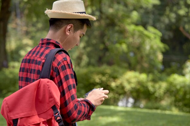 Foto un bel giovane turista felice che porta uno zaino nella foresta verde