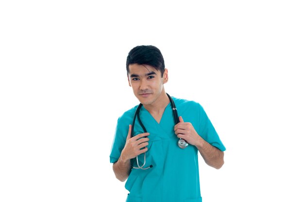 Handsome young male doctor with stethoscope in uniform posing isolated on white background